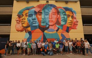 This is an image of MarketStar employees gathered in front of our "We Care" mural painted outside of the Ogden HQ office.