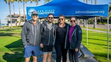  Four Opto Investments team members in front of a San Diego Coastkeeper tent.
