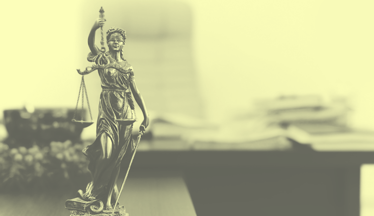 A yellow-toned image of a statue of Blind Justice holding her scales, set in front of an executive desk with chair and books. startup-chief-data-ethics-officer