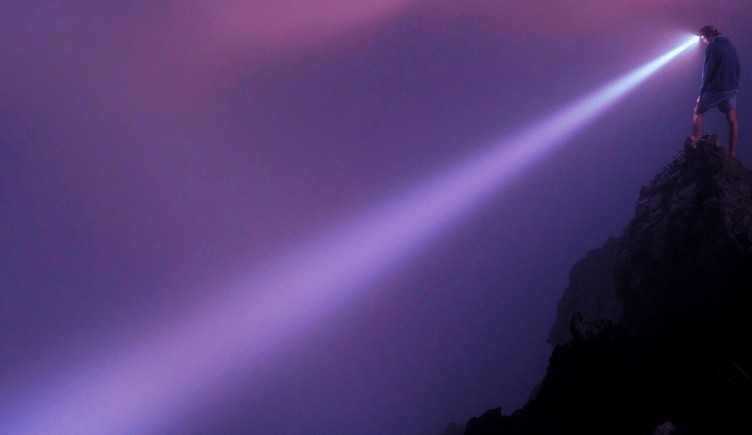 A person job searching through thick fog with a flashlight.