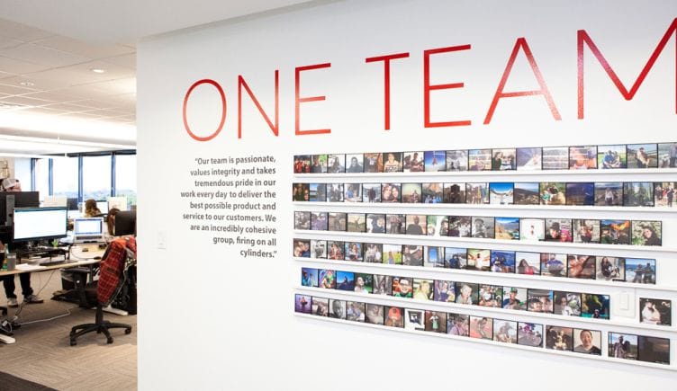 One Team wall with photographs inside AlertMedia office