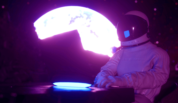 A person moonlighting as an astronaut while working on a laptop with the moon looming in the background.
