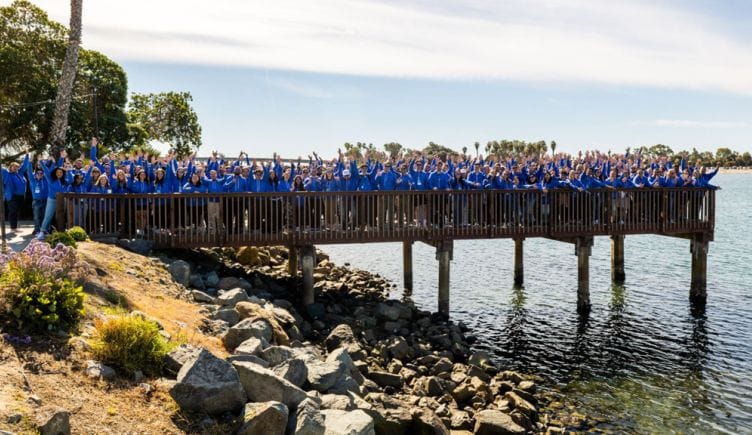 BetterCloud team members wearing blue shirts standing on a pier over the water