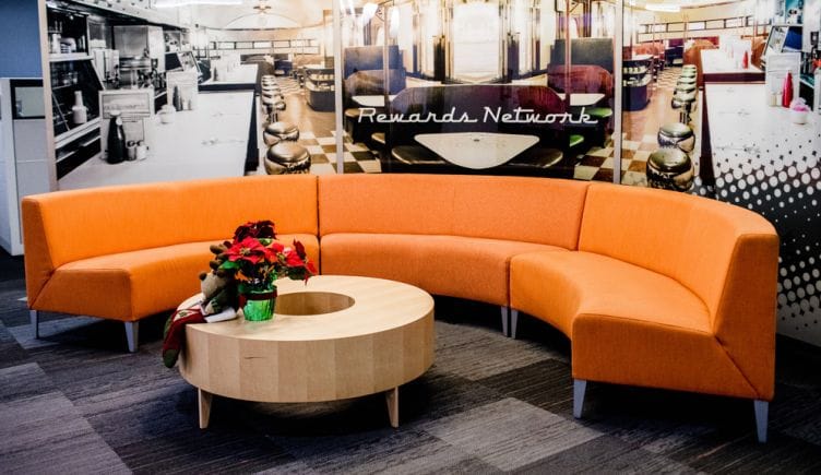 Orange couch in a sitting area in the Rewards Network office