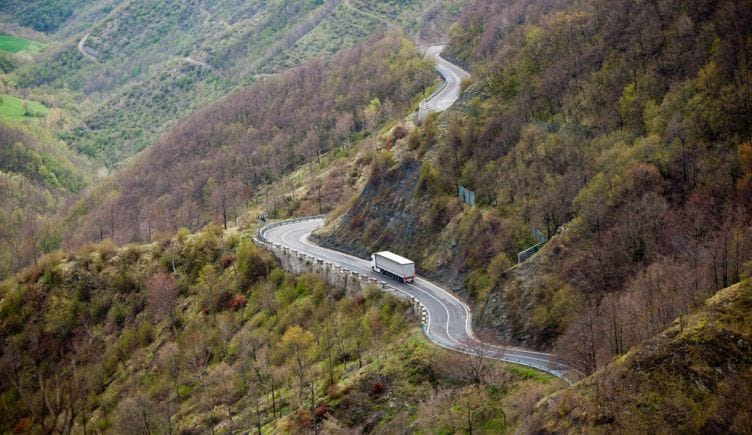 A truck driving on a long winding road through the mountains