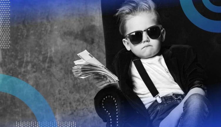 A child in a blazer, suspenders, sunglasses, sits in a wingback chair and waves a fistful of cash. /career-development/5-points-negotiate-executive-compensation