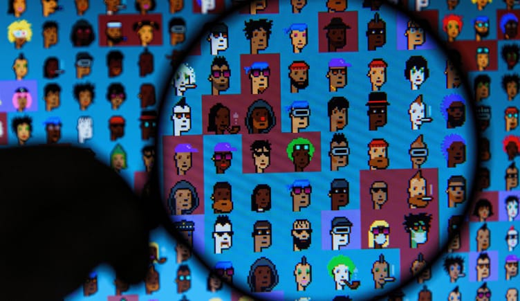 A person holding a magnifying glass to a screen filled with cryptopunks.