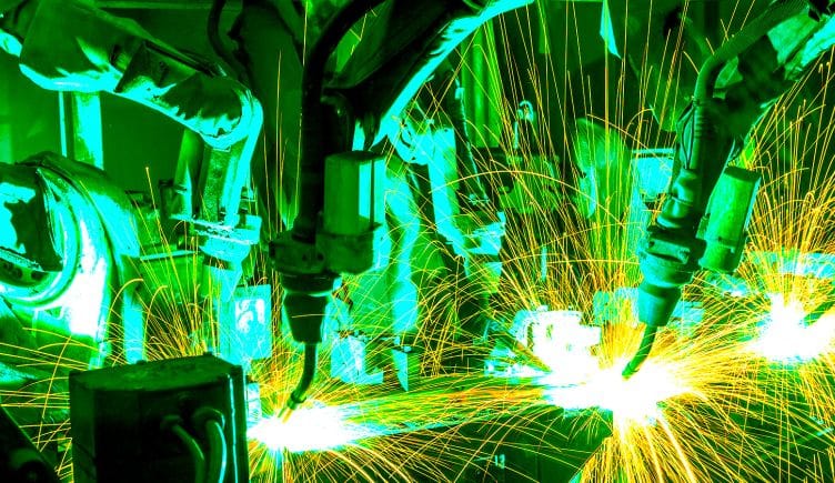 Industrial robots welding metal material on an assembly line.