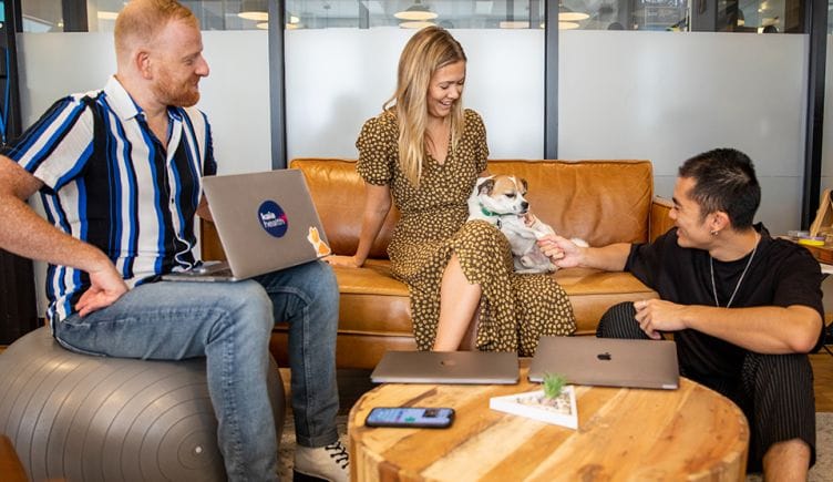 Employees at Kaia Health play with a dog in the office.