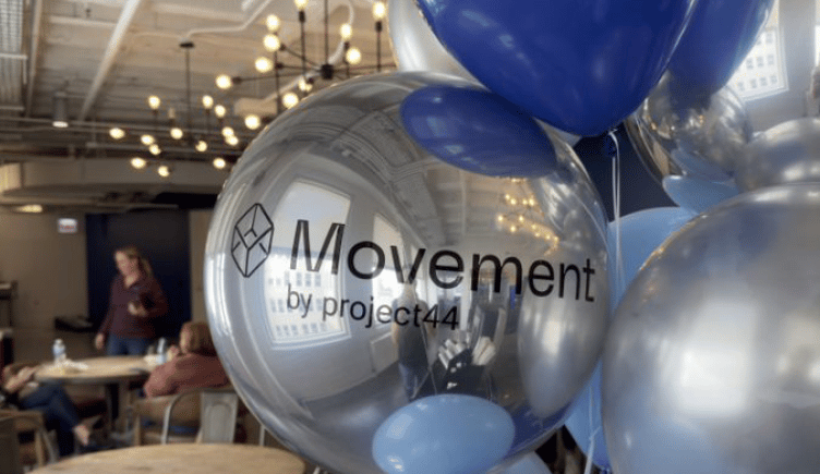 A cluster of metallic balloons emblazoned with the Movement logo. 