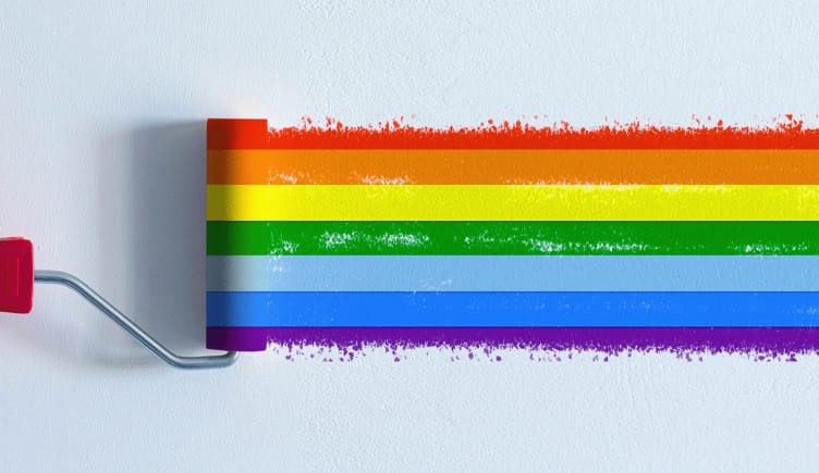 A paint roller painting a rainbow across a blank wall.