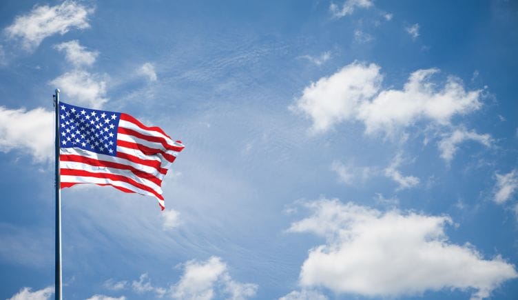 The American flag waves in front of a cloudy background