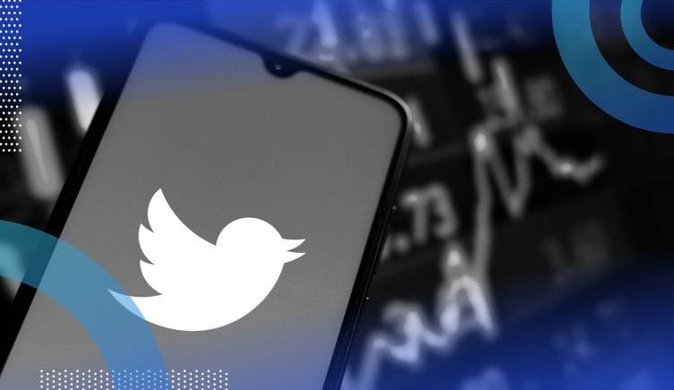 The Twitter logo on a smartphone in front of a stock ticker