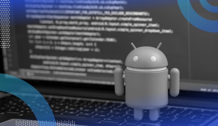 Android development image of the Android droid standing on the keyboard of a computer. Behind the figurine we can see a computer screen covered in code.