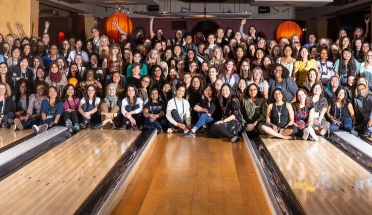 A large group of women from the Society of Women's Engineers, posing for a photo in a bowling alley.