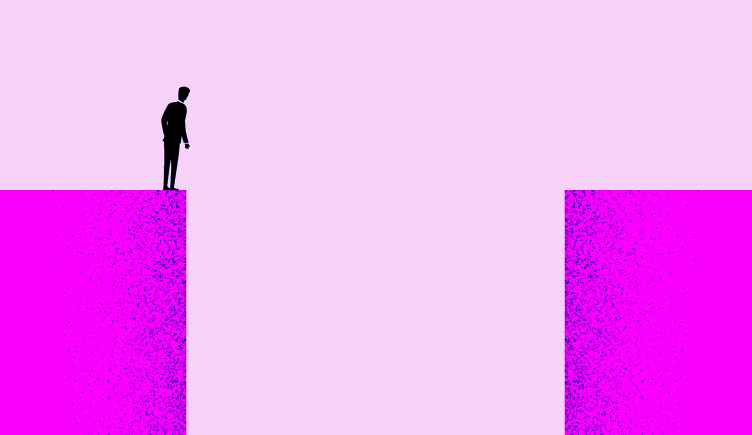 A person standing on one endo of a large gap looking down into it.