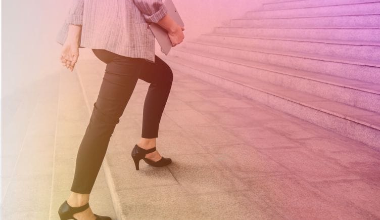 Photo of a woman in sensible heels and business casual clothes walking up stairs. There's a golden and pink gradient overlay. 