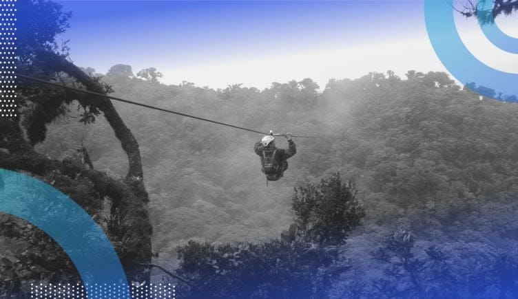 A person traversing trees on a zip line.