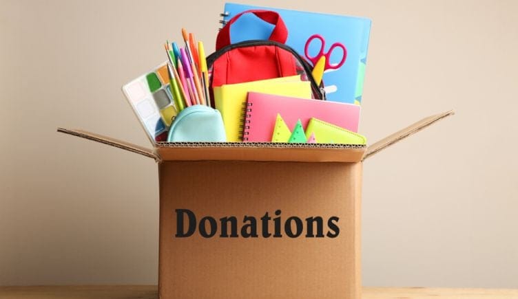 Notebooks, pens and other school supplies fill a donation box.