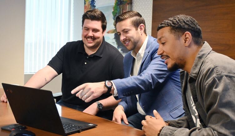 Photo of three Center team members pointing at computer screen