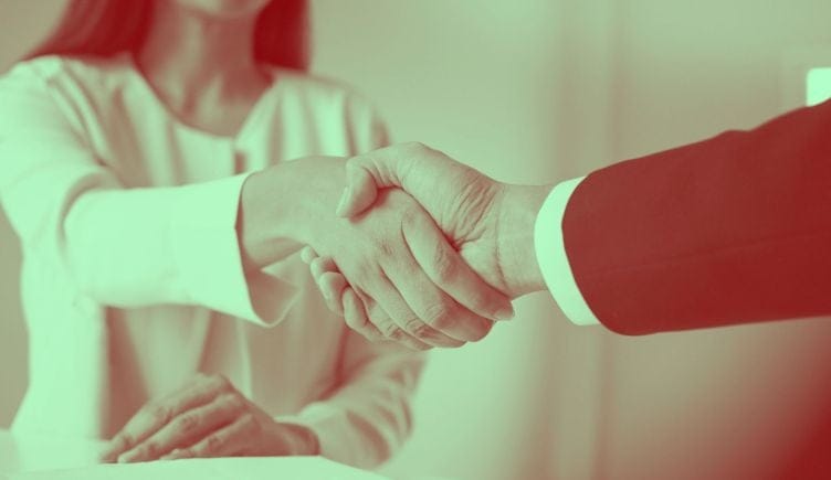 An applicant accepts a job offer by shaking the hiring manager's hand.