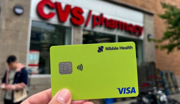  Photo of hand holding Nibble Health Visa card in front of CVS Pharmacy