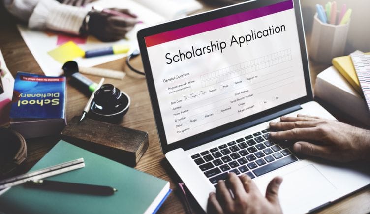 A scholarship application is open on a laptop screen.