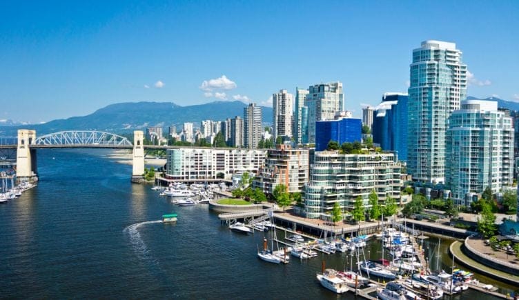 A view of the Vancouver skyline that includes several tall buildings and a bridge over the water.