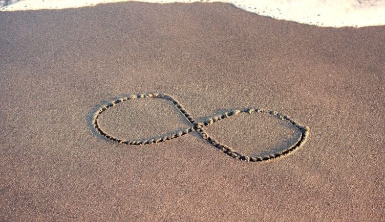 an infinity symbol carved into a sandy beach