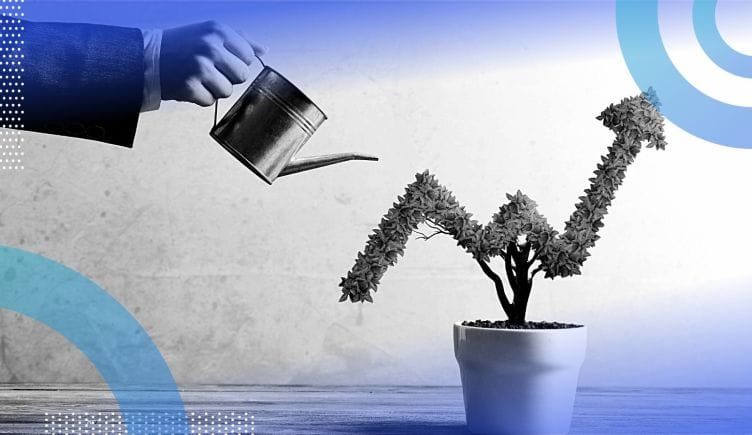 The hand of a business woman watering a plant in the shape of an upward arrow.