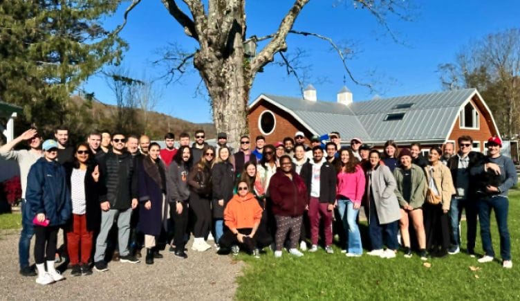 Large group photo of Findigs team members outside with a red barn-like structure in the background