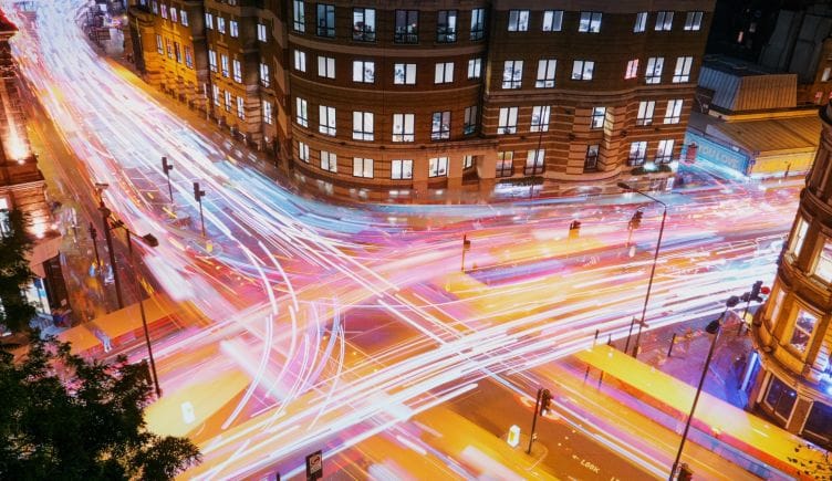 London vehicle traffic is photographed with a long exposure, creating colorful streaks of light.