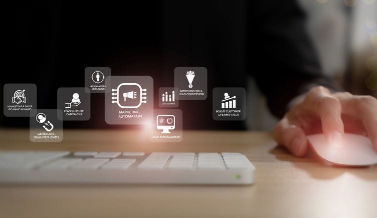  Image of a person using a mouse and keyboard with a graphic overlay of icons conveying the concept of marketing automation.