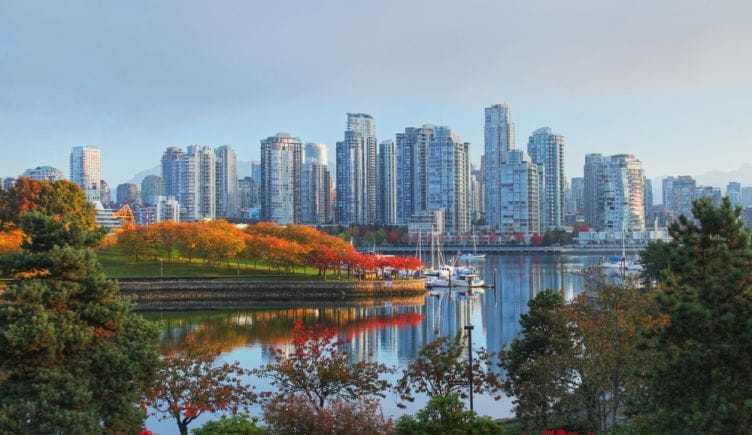 A view of the Vancouver skyline with trees in the forefront and several buildings in the background.
