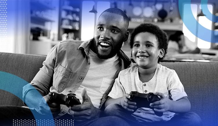 A father and son smiling while playing video games together.