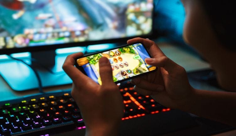 A close up of a pair of hands holding a smartphone and playing a mobile game.