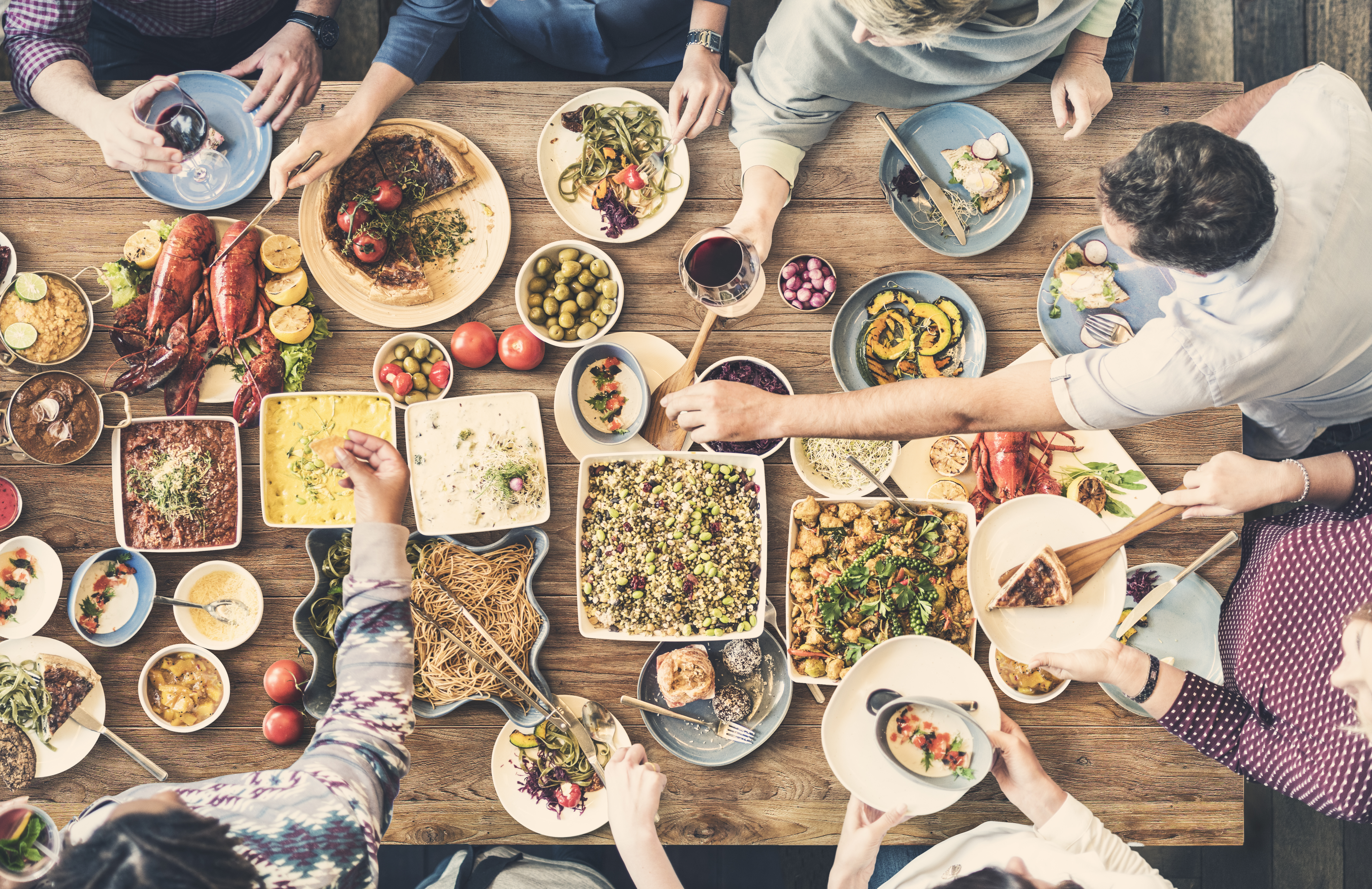 An aerial-view image of friends gathered around a table eating and drinking together.