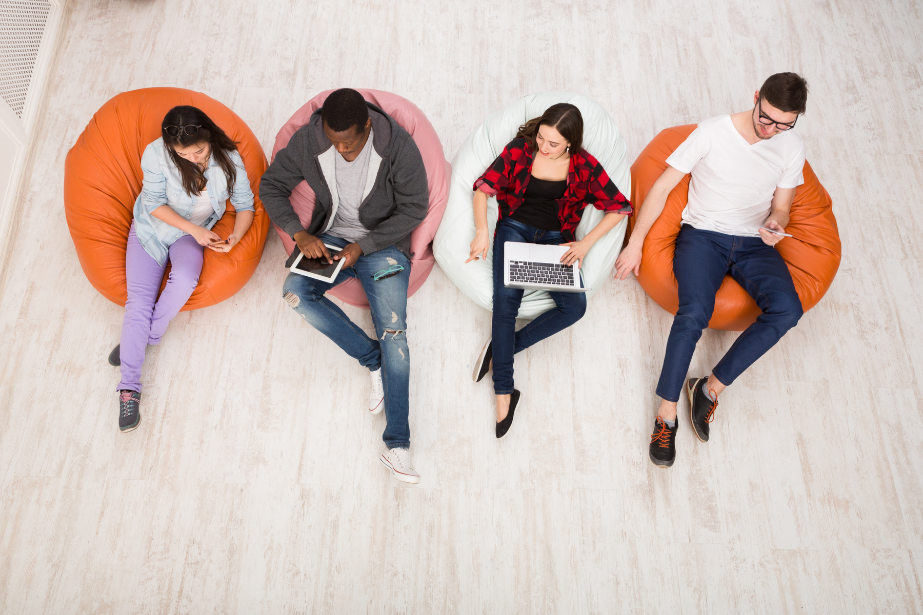Young people sit in beanbags using gadgets