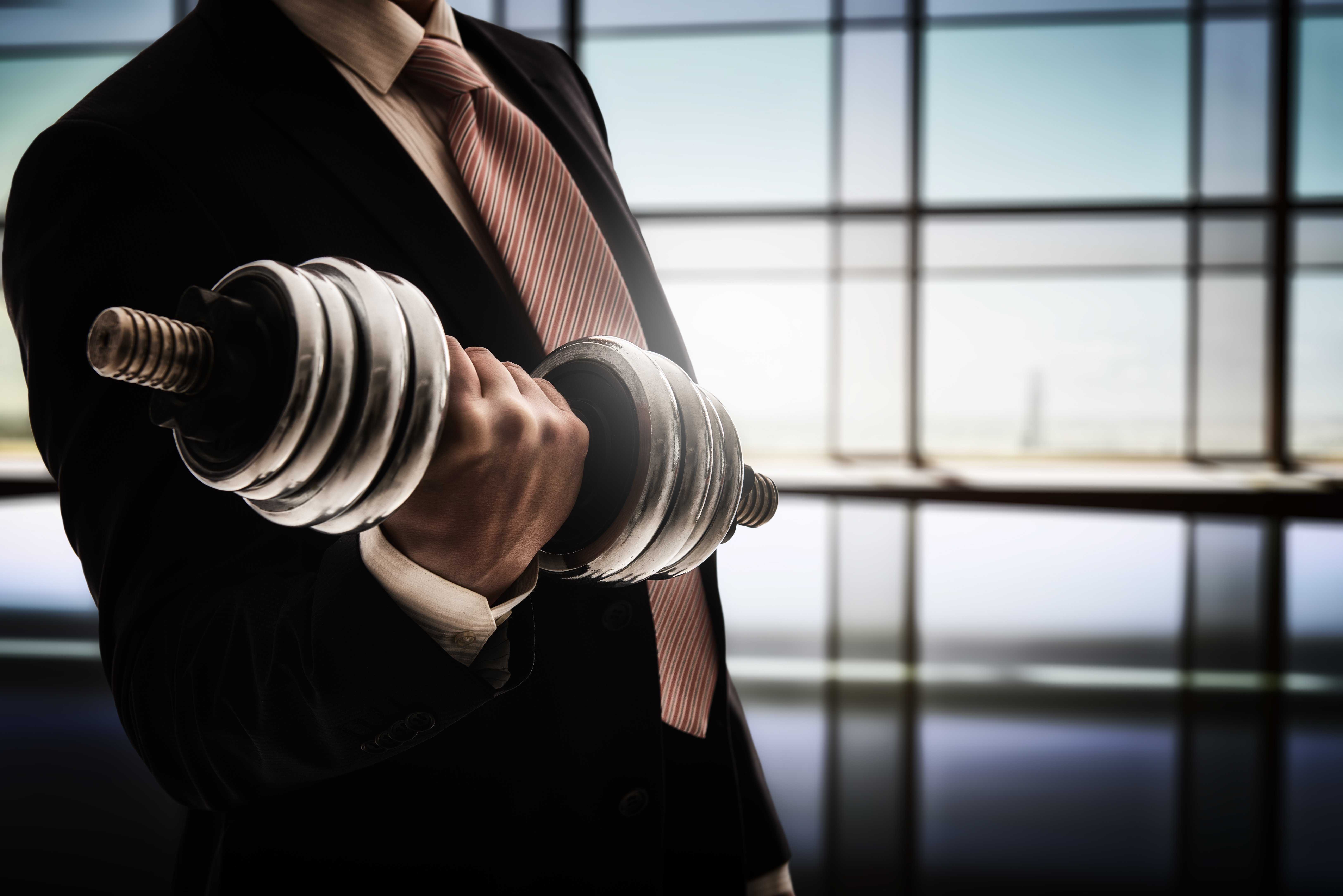 A man in a business suit lifting weights for muscle development.