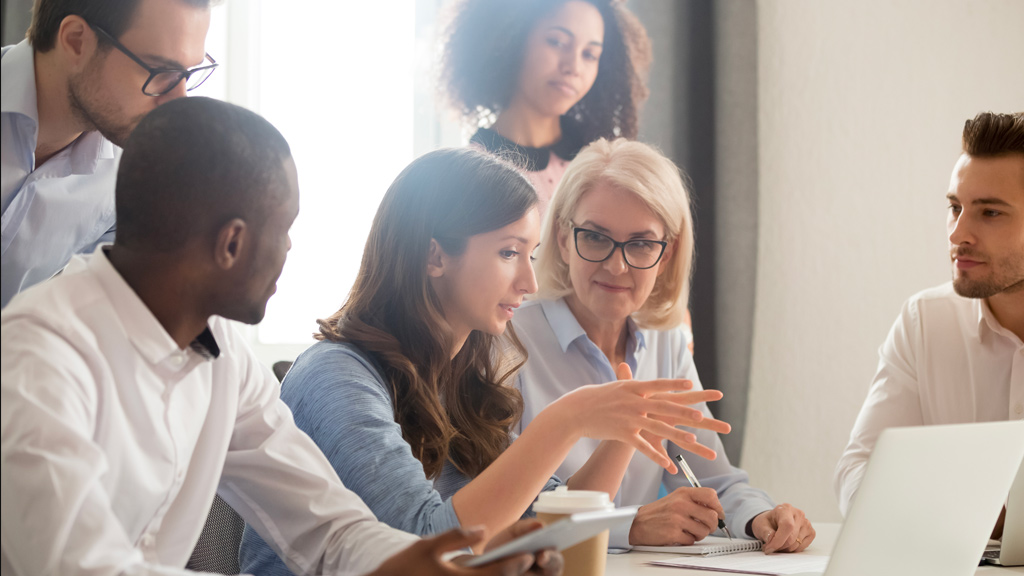 Manager explaining business strategy to team members looking at a laptop in the office