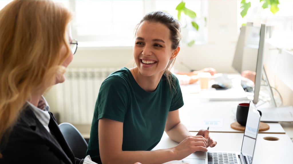 Two happy female colleagues looking at a laptop