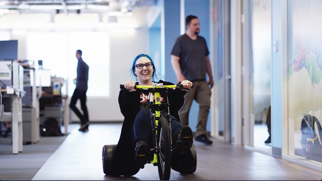 SciPlay team member riding a bigwheel in the office