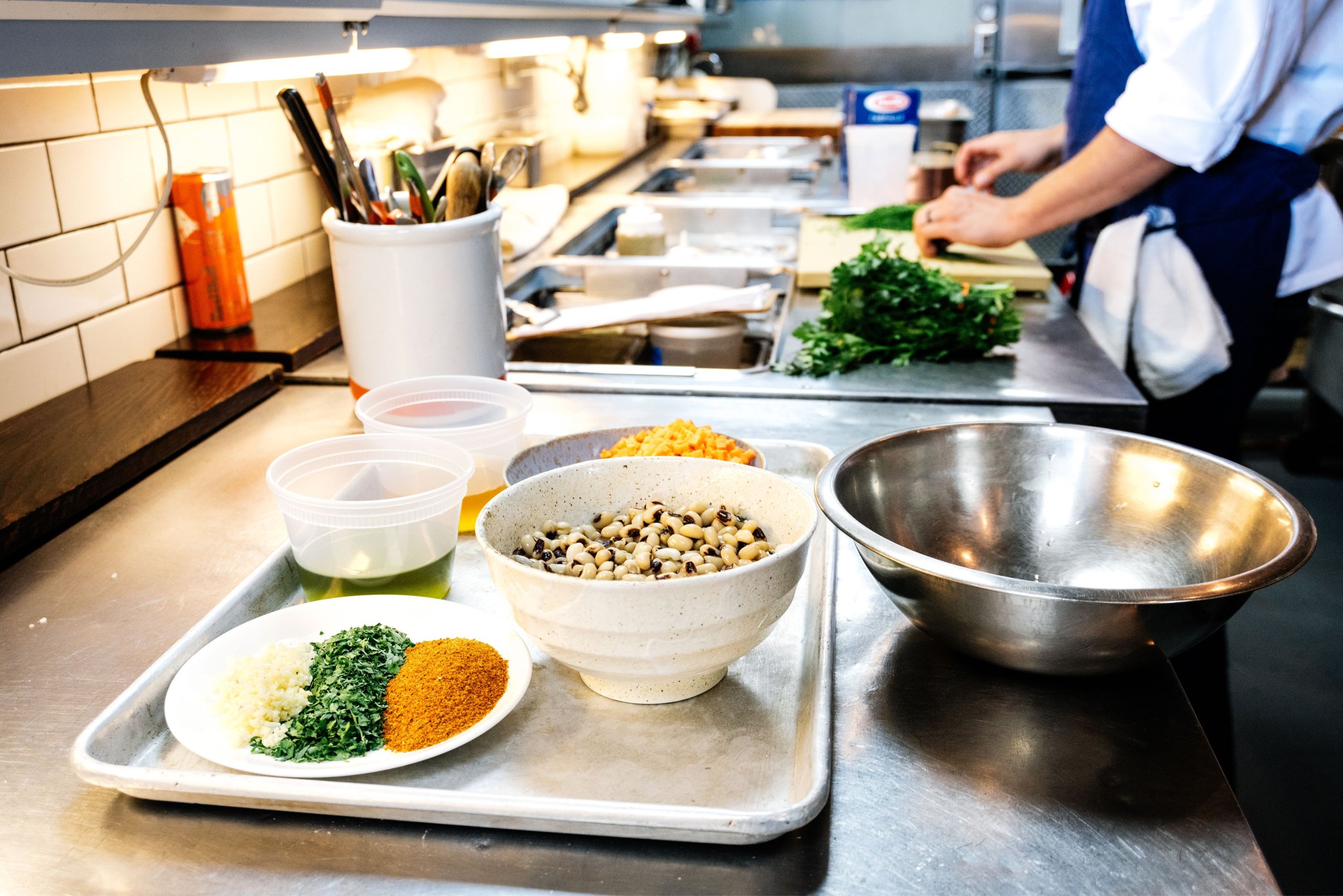 professional kitchen with ingredients prepped and cook chopping in the background
