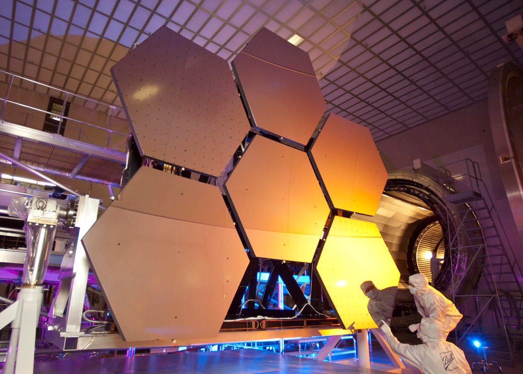 A scientist looking over several large, hexagonal panels of metal in a lab.