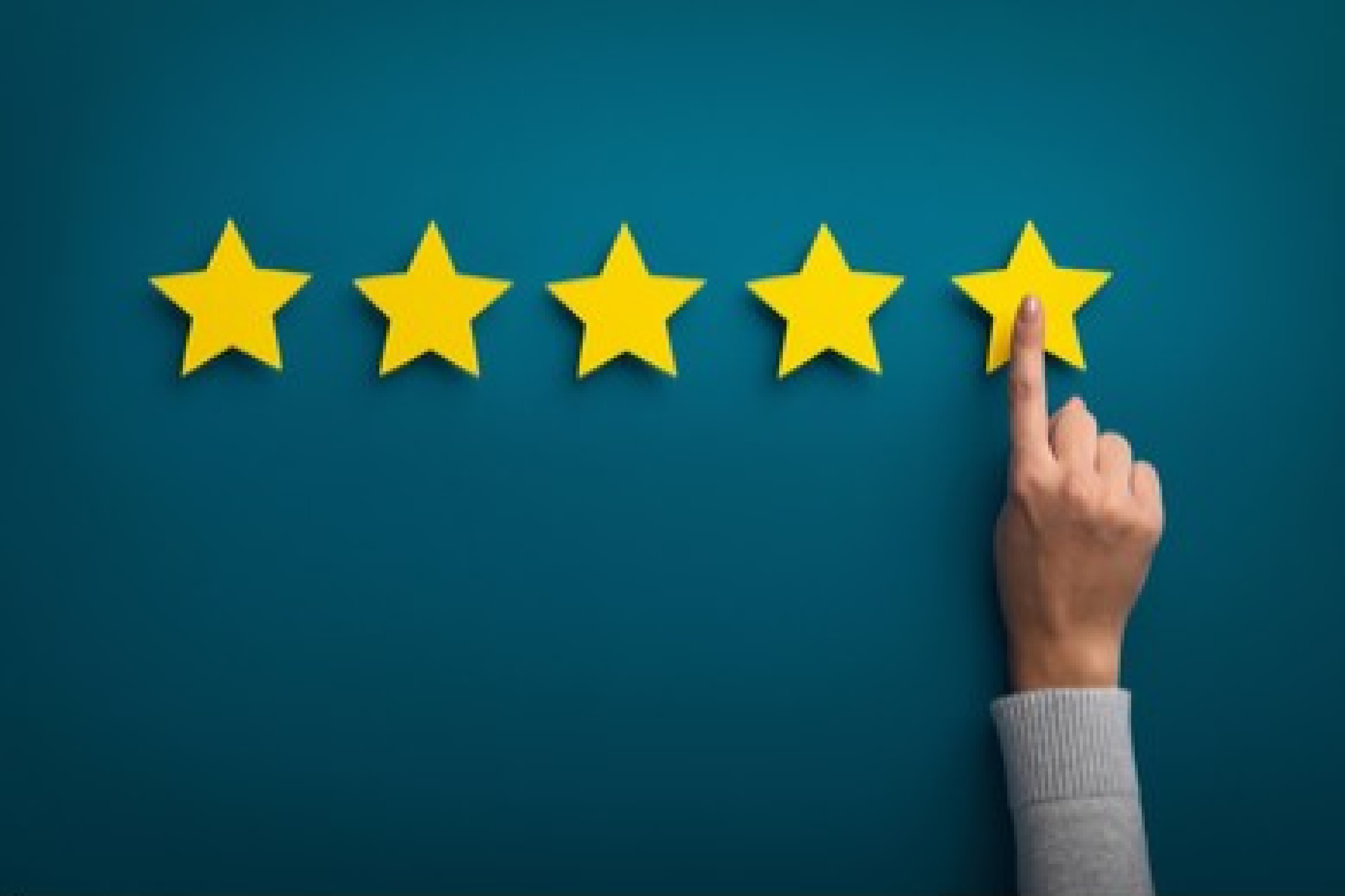 Concept photo of a five star rating with a hand selecting one star