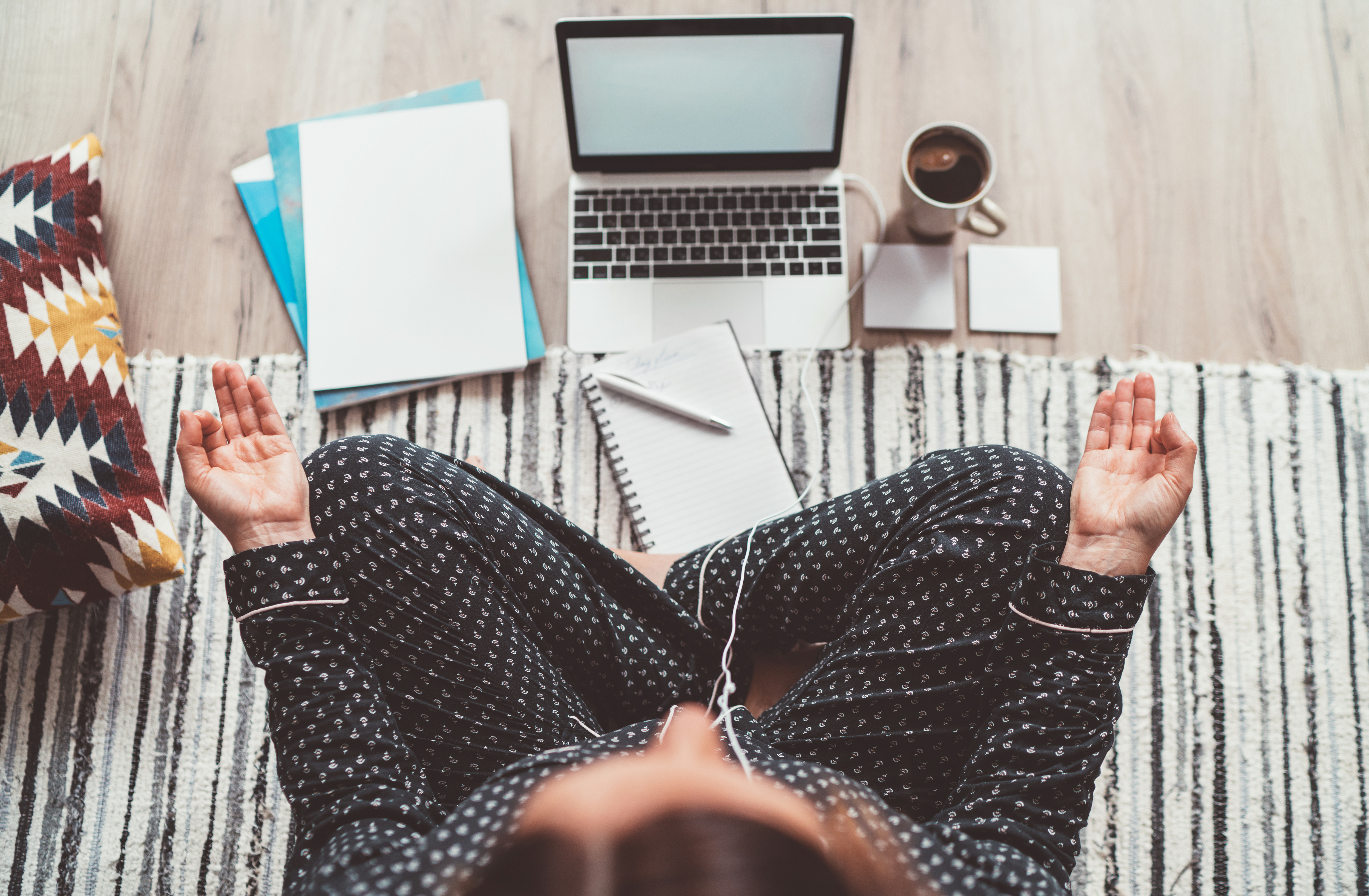 A woman meditates in front of her computer.