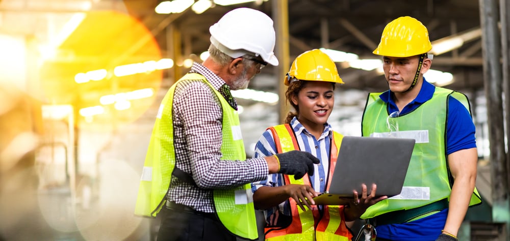 A construction crew looking at a laptop.