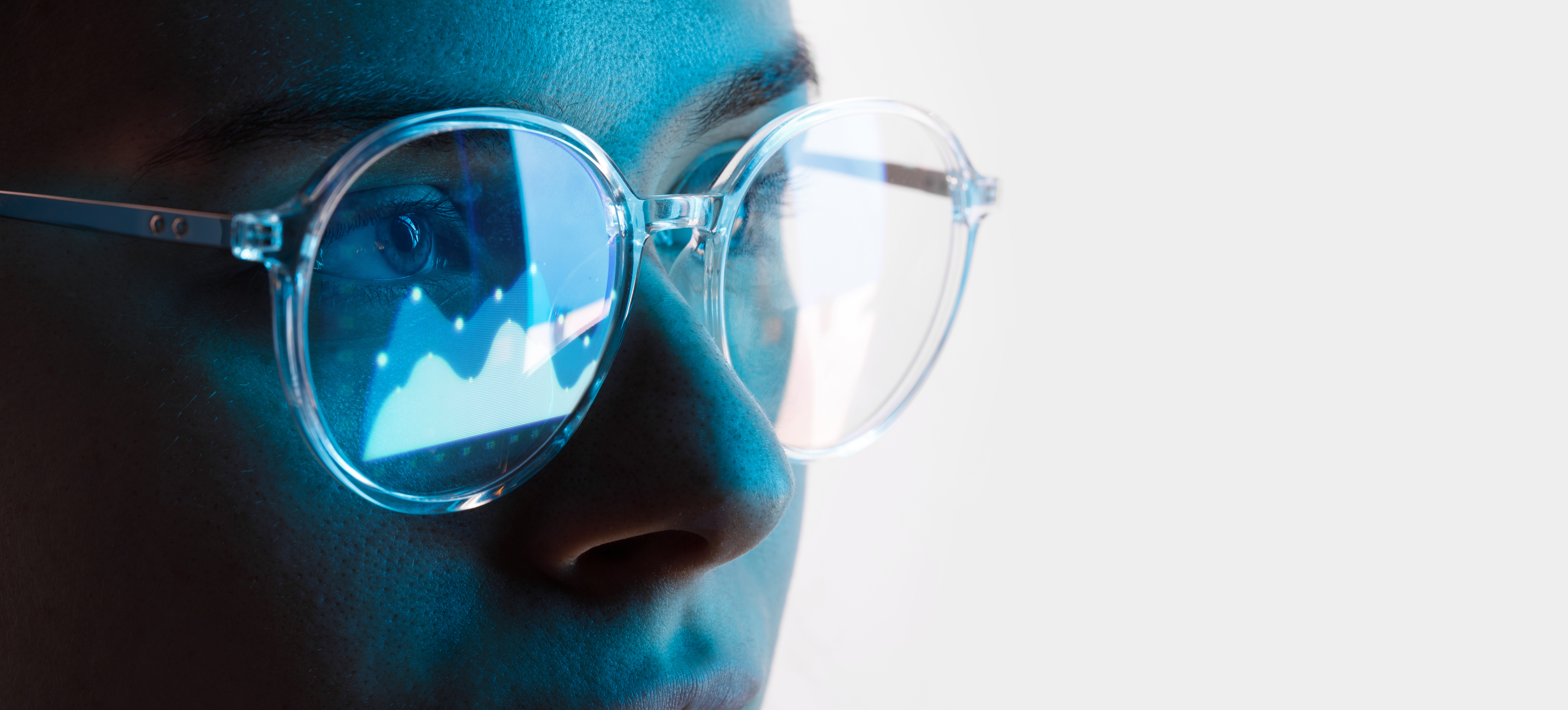 A person wearing glasses with data in the reflection.