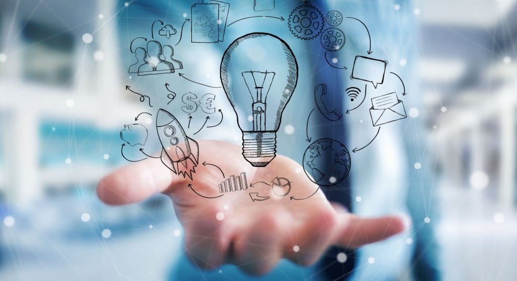 A hand holding a hand drawn lightbulb surrounded by multimedia icons.