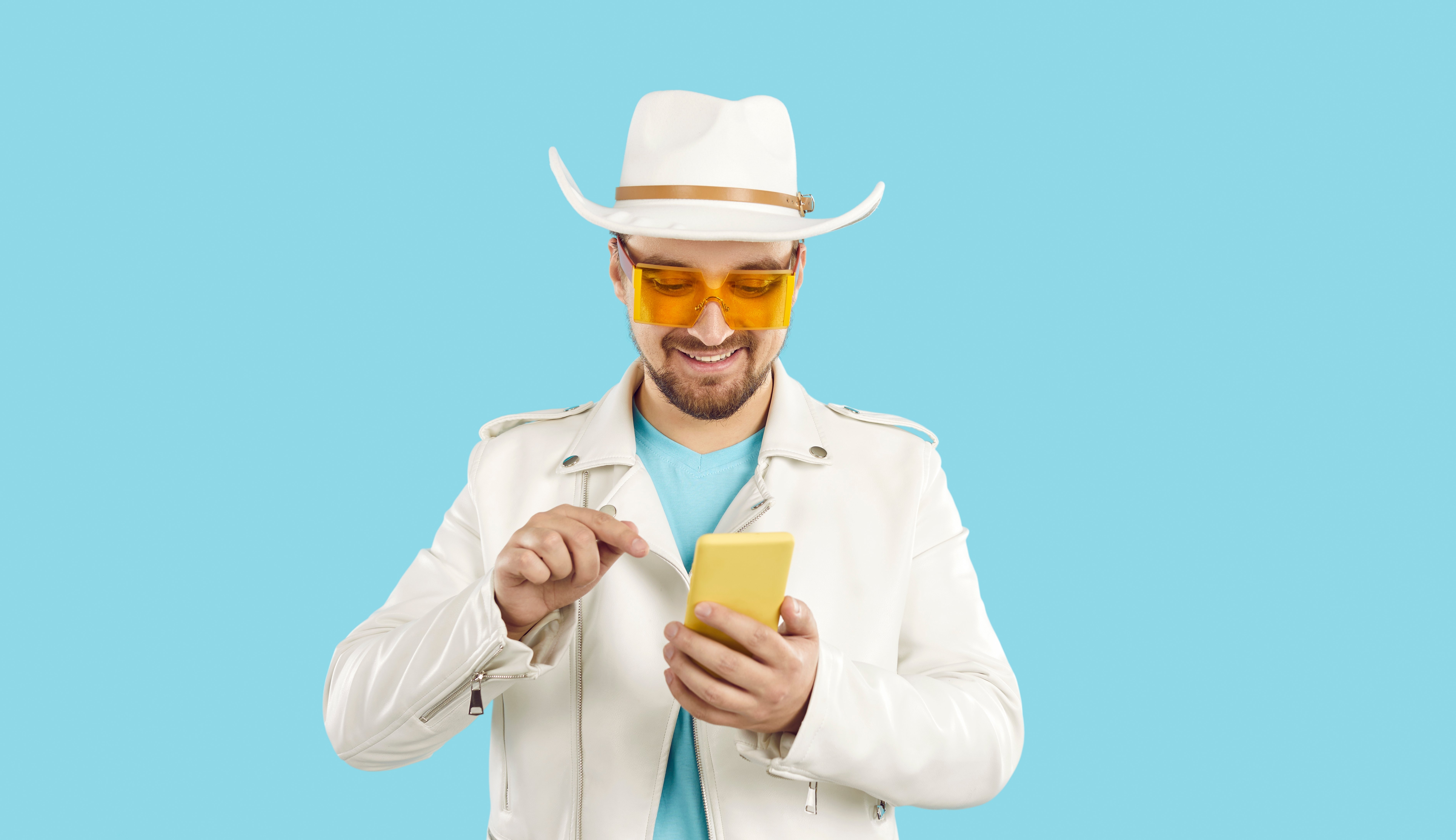 A man in Western wear types on his phone.